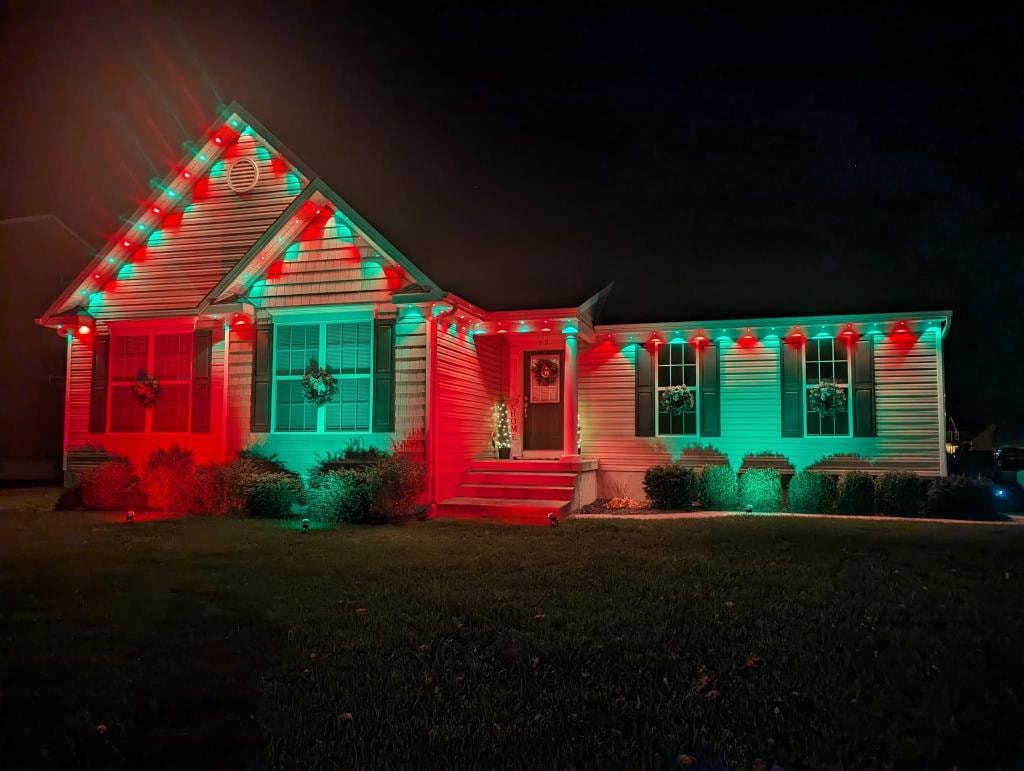 Ranch home with alternating red and teal Christmas roofline lighting