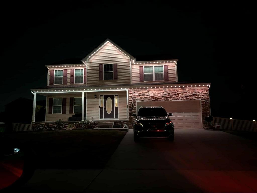 Stone colonial home with warm white roofline lighting